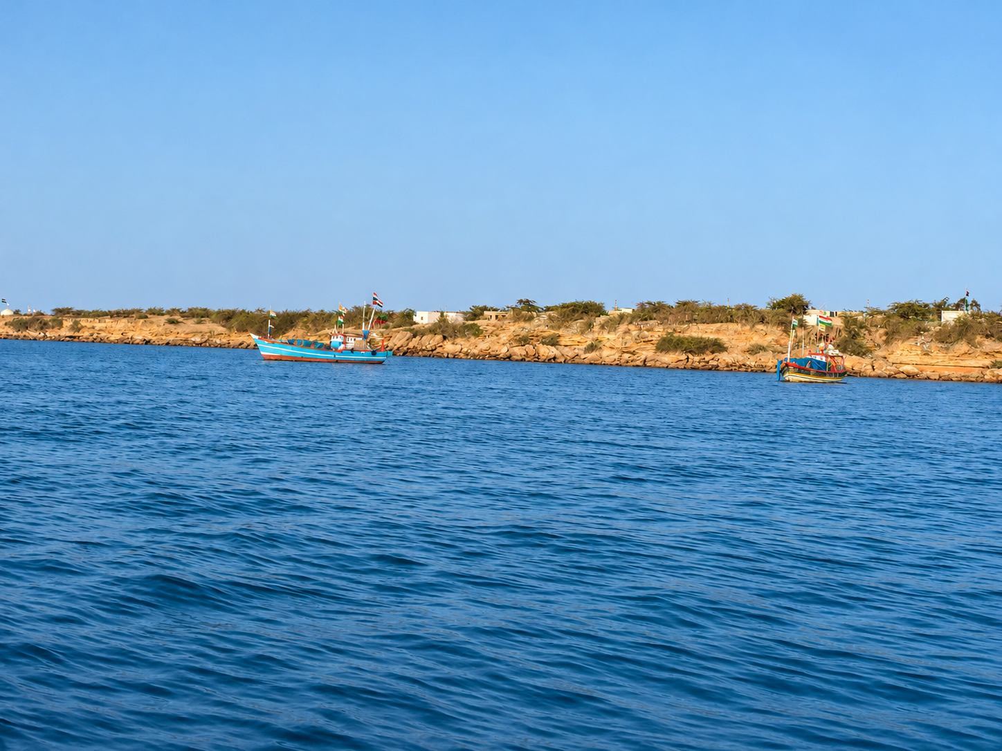 Boats beside the dry rocky coast of Bet Dwarka, with no people visible.