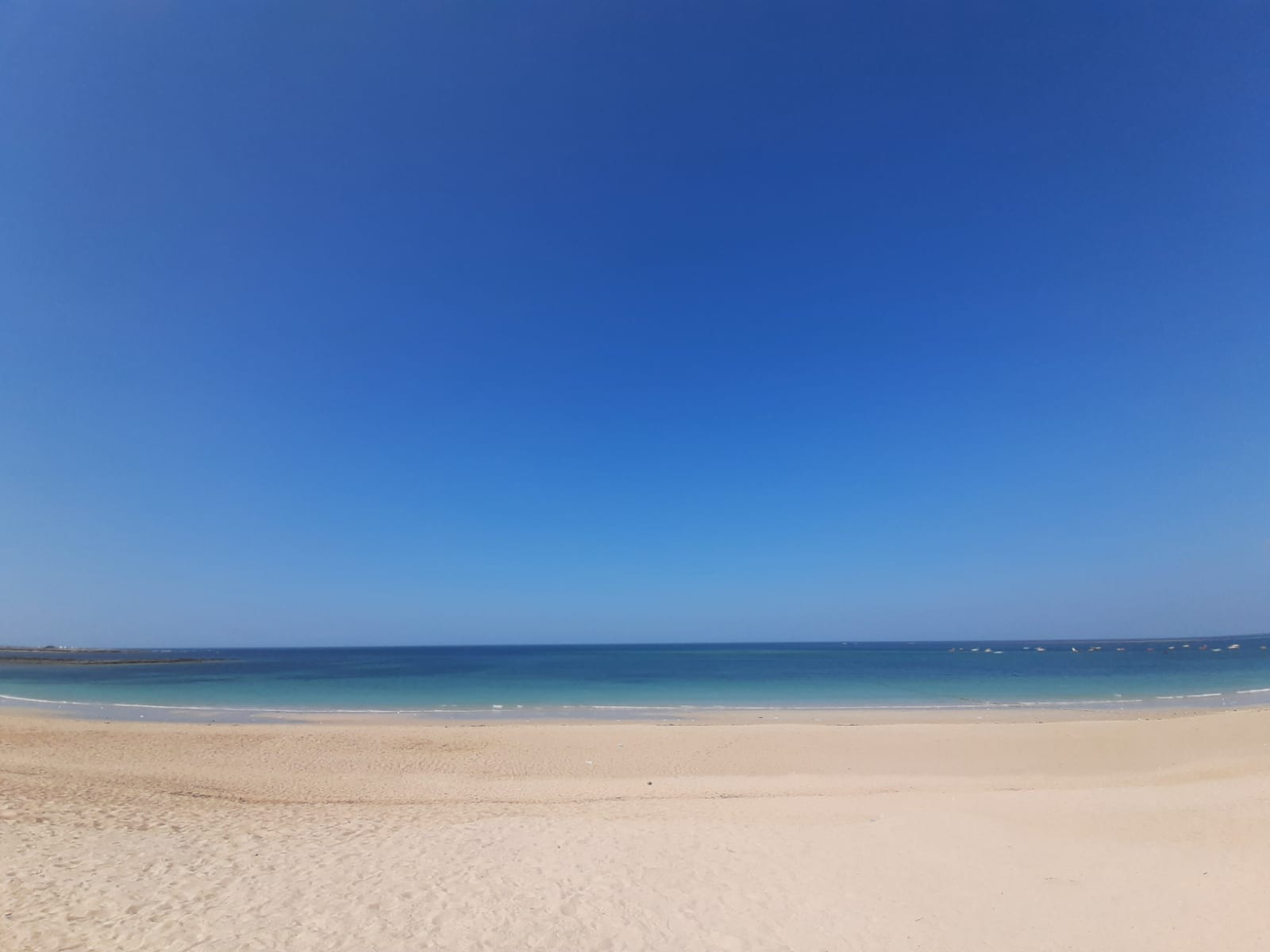 The empty sand and blue water of Shivrajpur Beach.